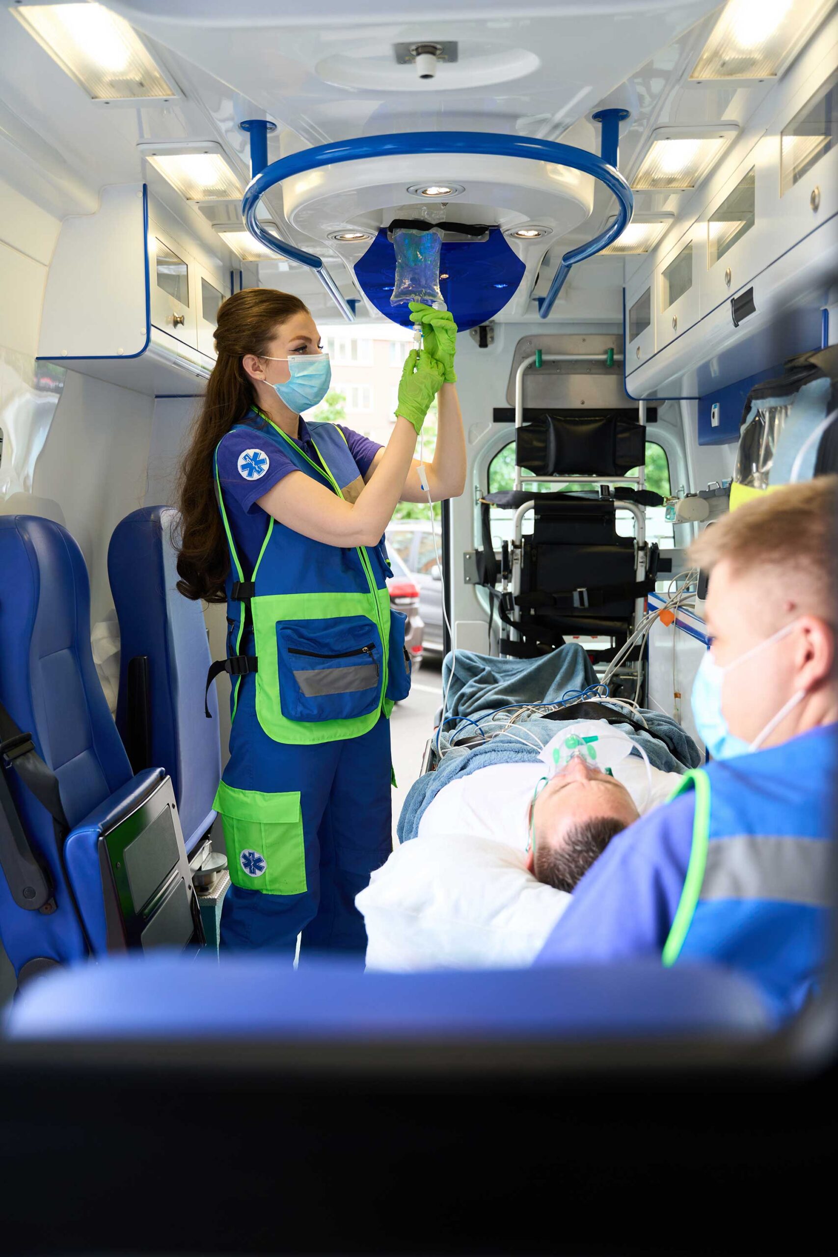 Female doctor puts an iv on patient in an ambulance